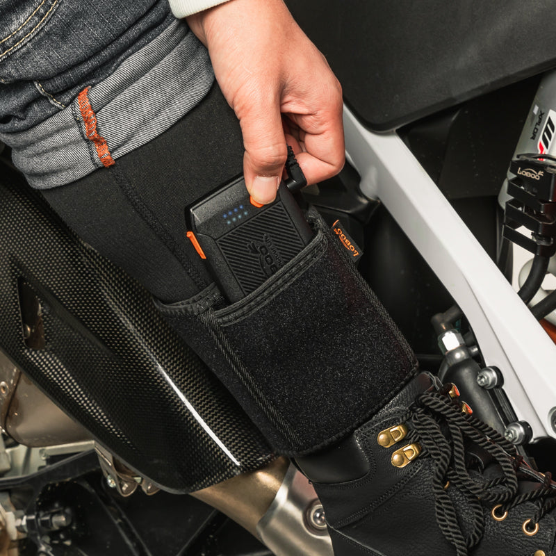 Power bank inserito nella fascia da polpaccio sopra lo stivale da moto