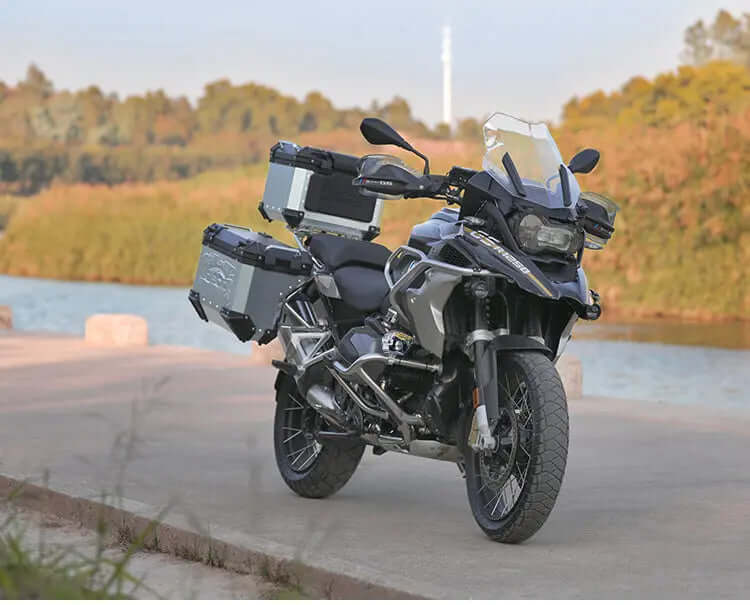 BMW GS con valigie laterali e bauletto in alluminio montati, parcheggiata in riva a un lago